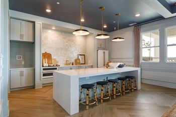 A kitchen with a white island and blue stools.